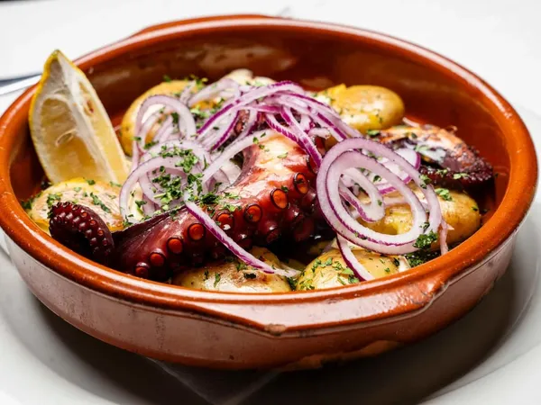 Octopus with red onions in a clay dish