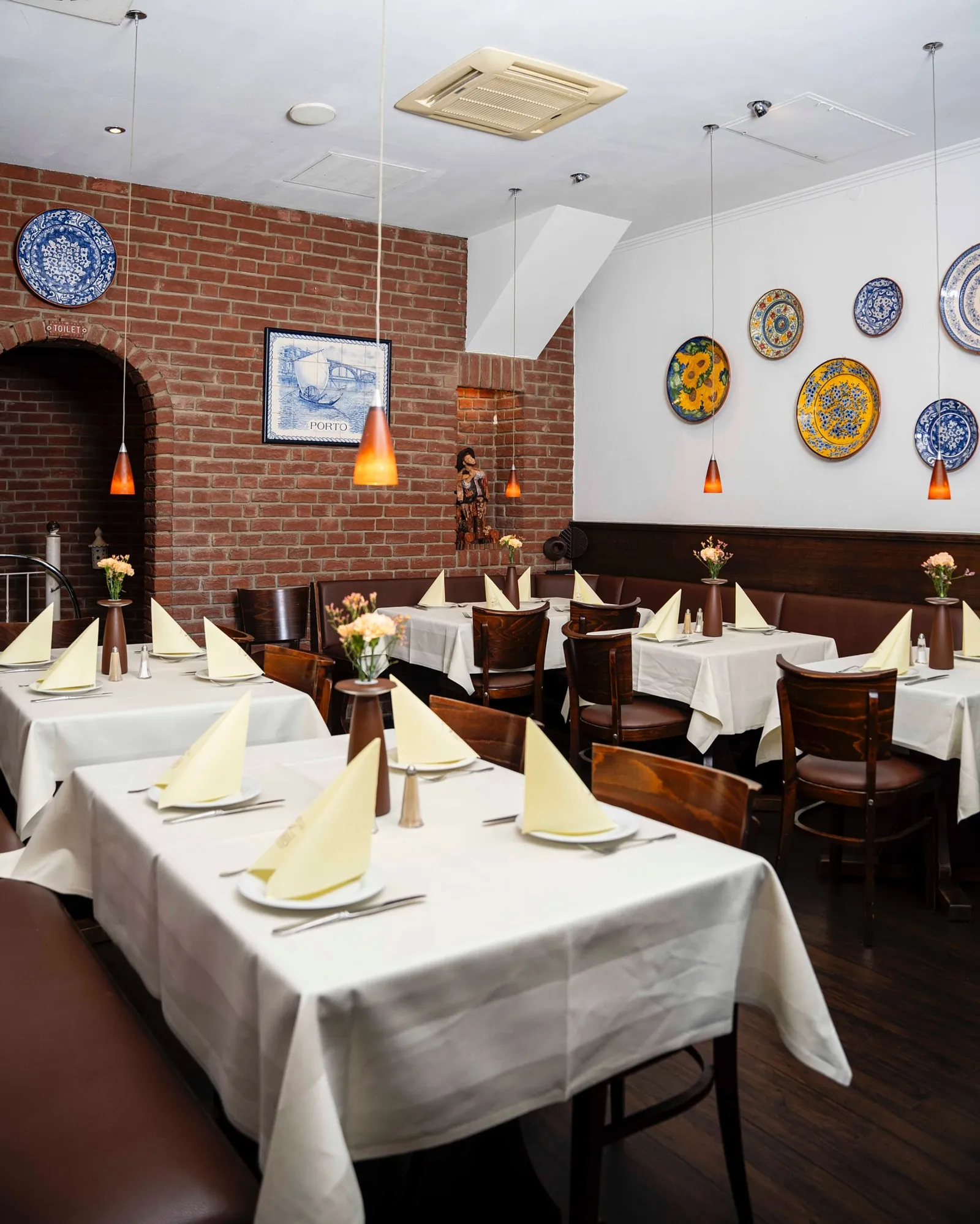 A sala luminosa do Restaurante Porto com pratos portugueses na parede